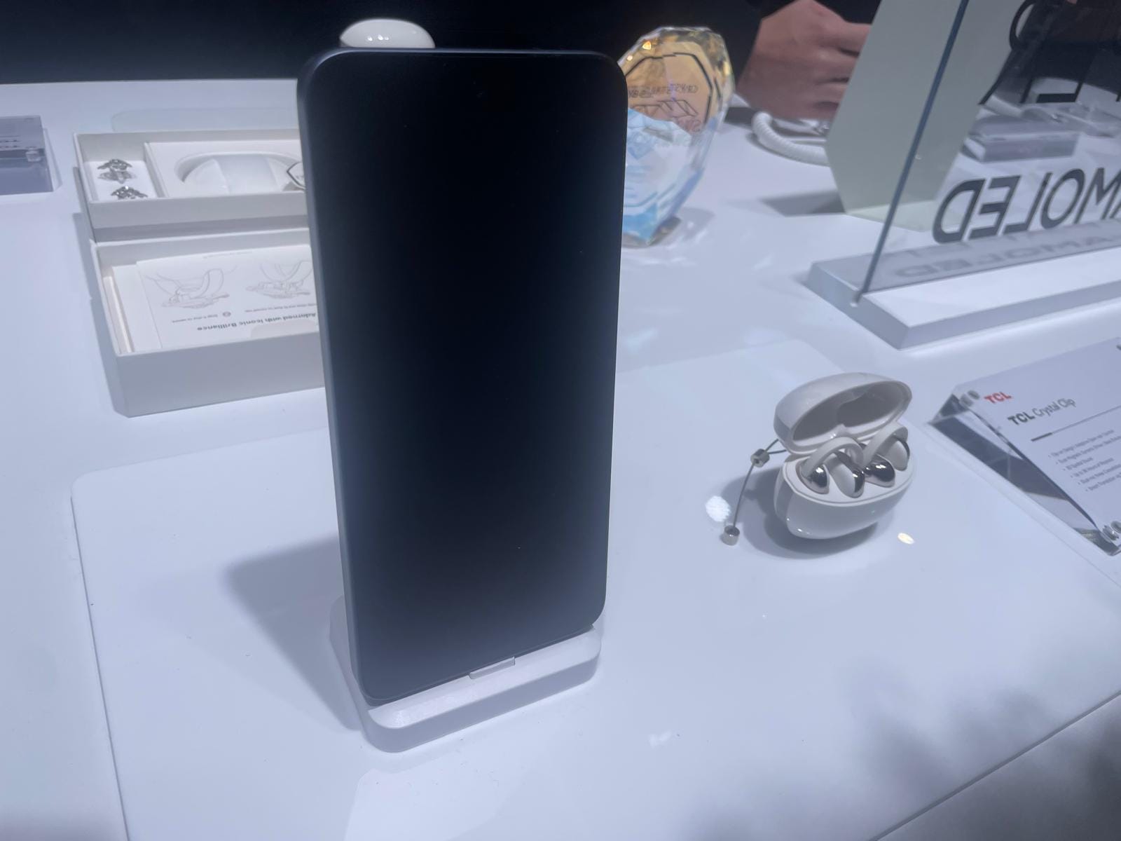 Fotografía de los auriculares TCL CrystalClip junto con un teléfono de la misma marca durante su presentación en el MWC 2026 de Barcelona