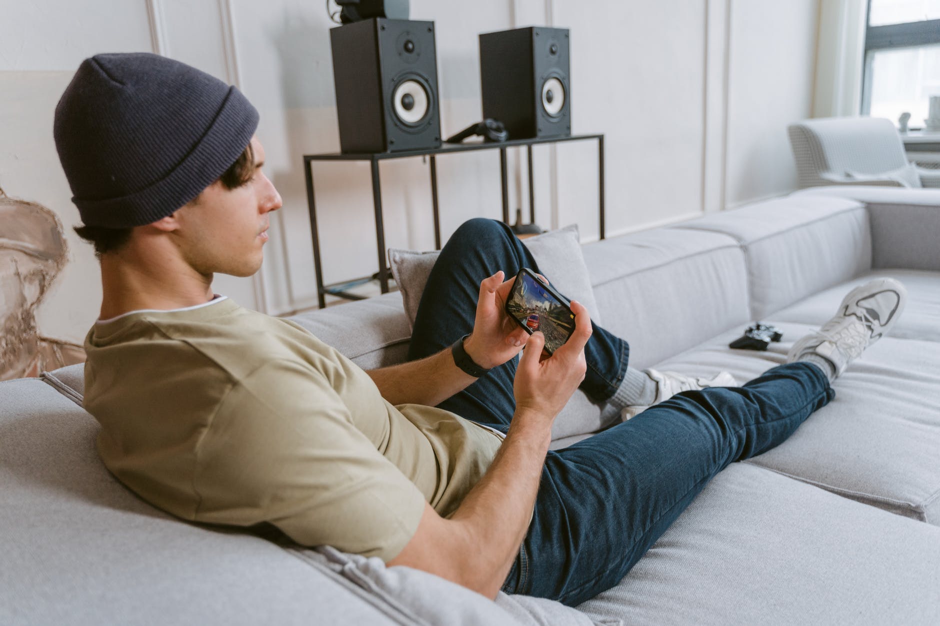 man in a shirt and blue denim jeans sitting on the couch