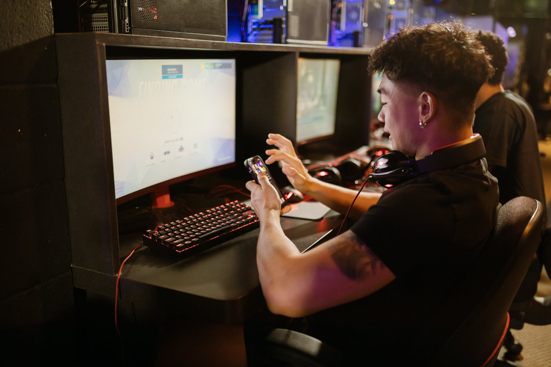 man in black shirt using a smartphone while sitting by the gaming computer